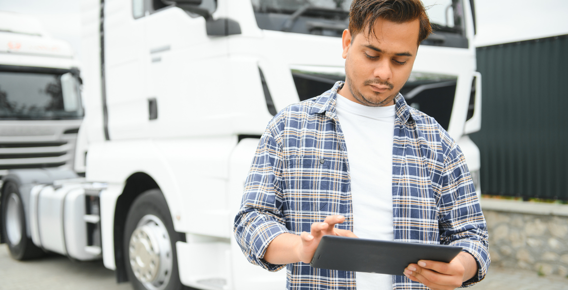 a man in front of truck checking on a tab